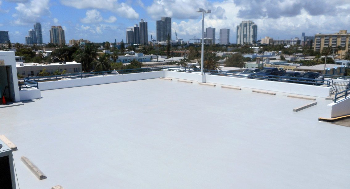 Rooftop parking deck coated in a light gray DriveDeck finish, with a city skyline behind it